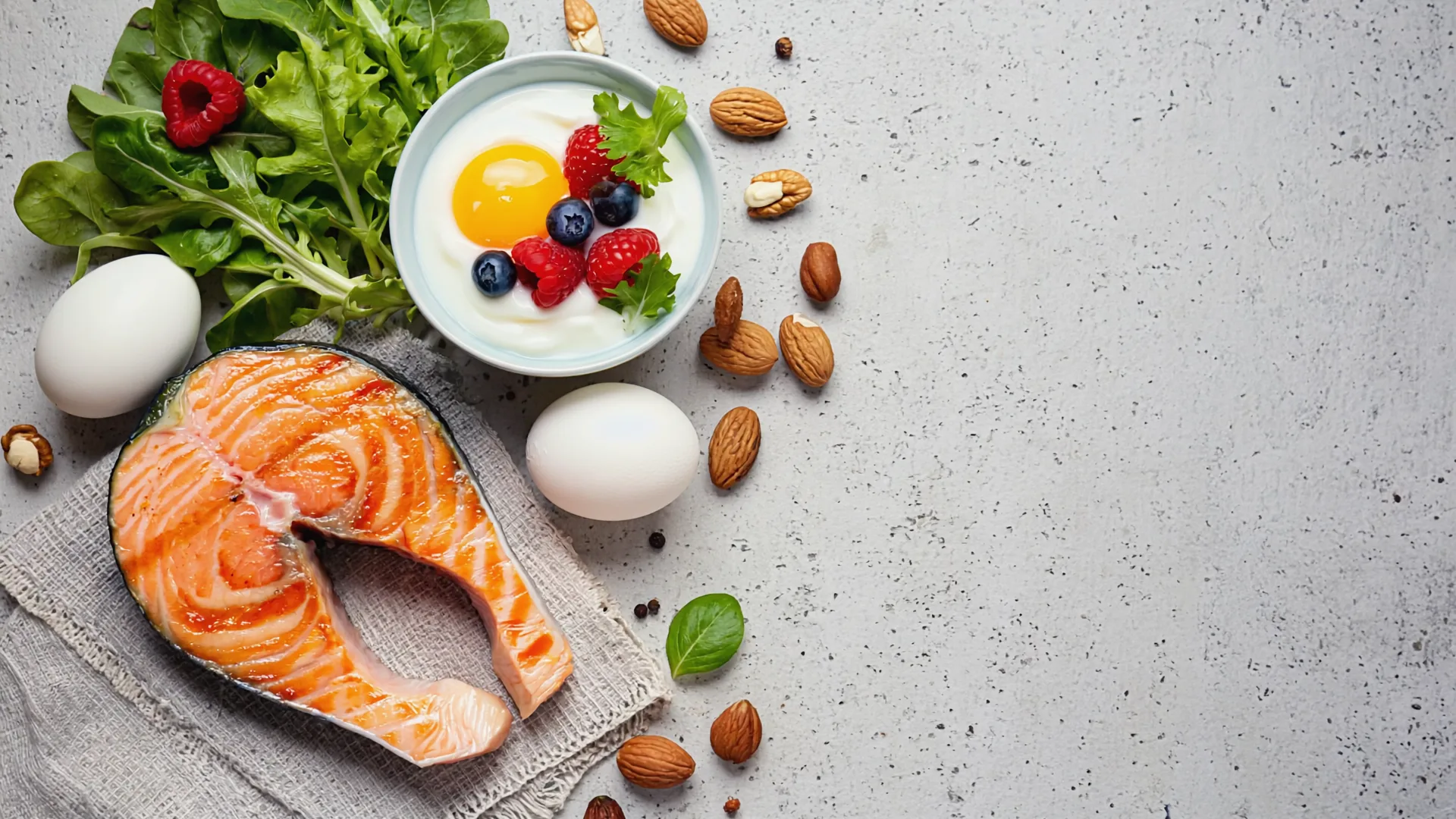 A high-protein meal of grilled salmon, eggs, yoghurt and leafy greens arranged on a light kitchen counter