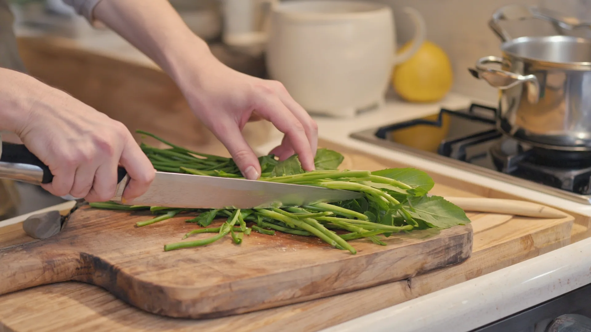 Whatever the approach, most of the day-to-day work happens in an ordinary kitchen Hands chopping green vegetables on a wooden board in a bright home kitchen with a steaming pot on the hob