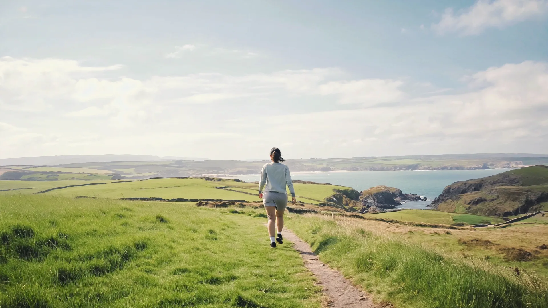 A person walking briskly along a green coastal path in Ireland as part of a healthy lifestyle