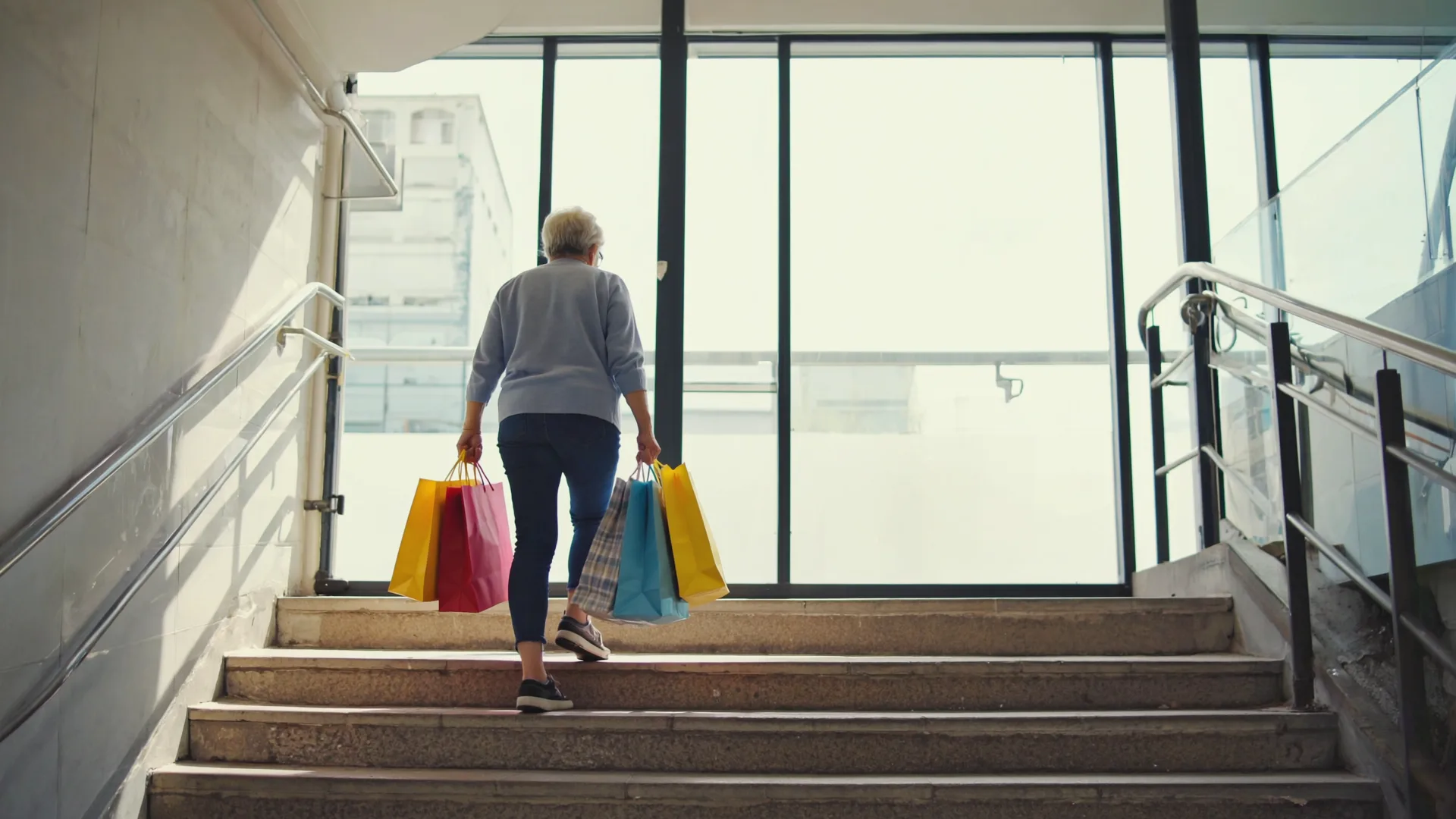 An older adult carrying shopping bags up a flight of stairs in everyday life, strong and capable