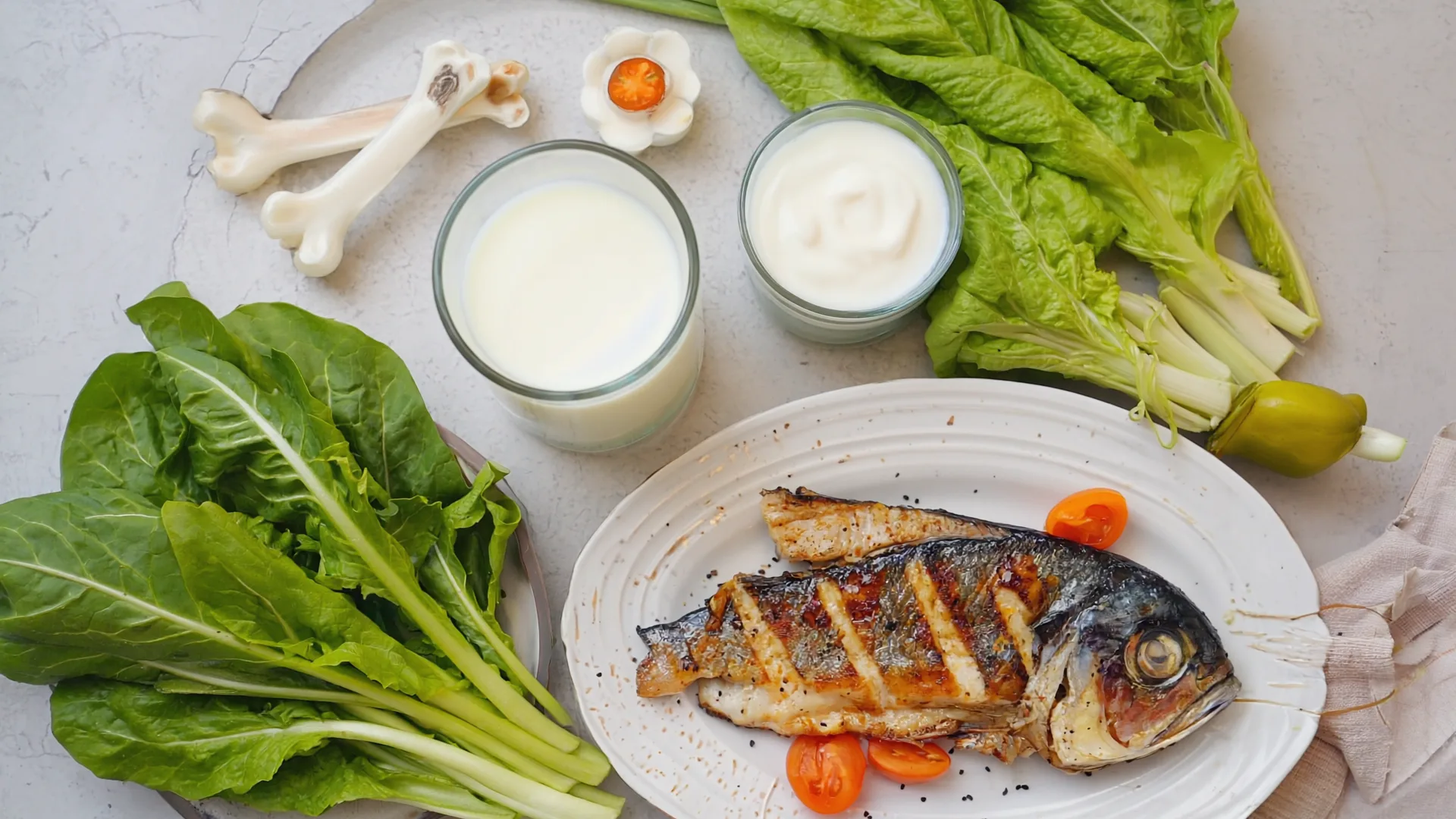 A wholesome bone-friendly meal of leafy greens, dairy and grilled fish on a table in natural light
