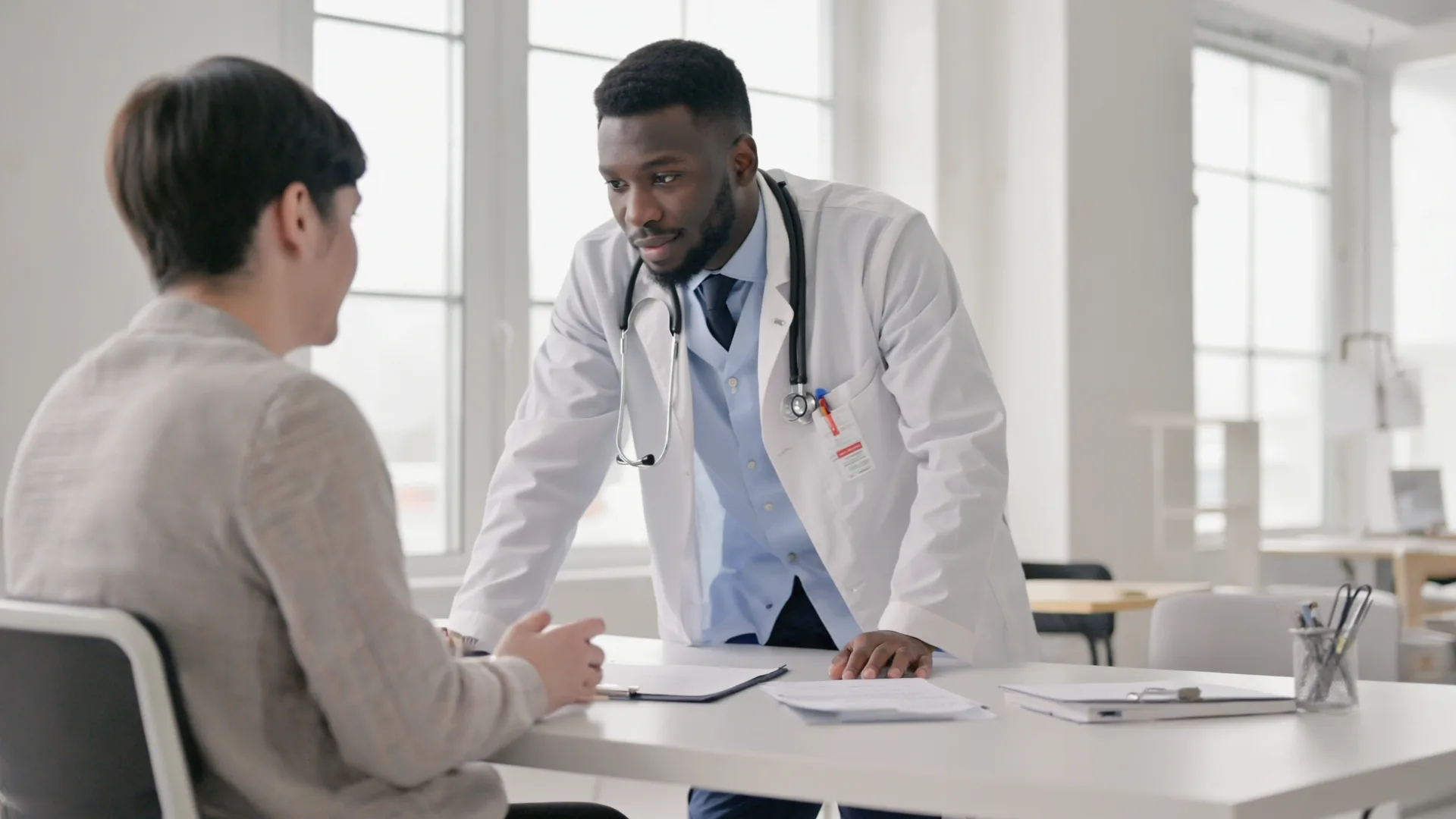 A doctor and patient in a calm conversation across a desk in a bright modern Irish clinic A doctor and patient in a calm conversation across a desk in a bright modern Irish clinic
