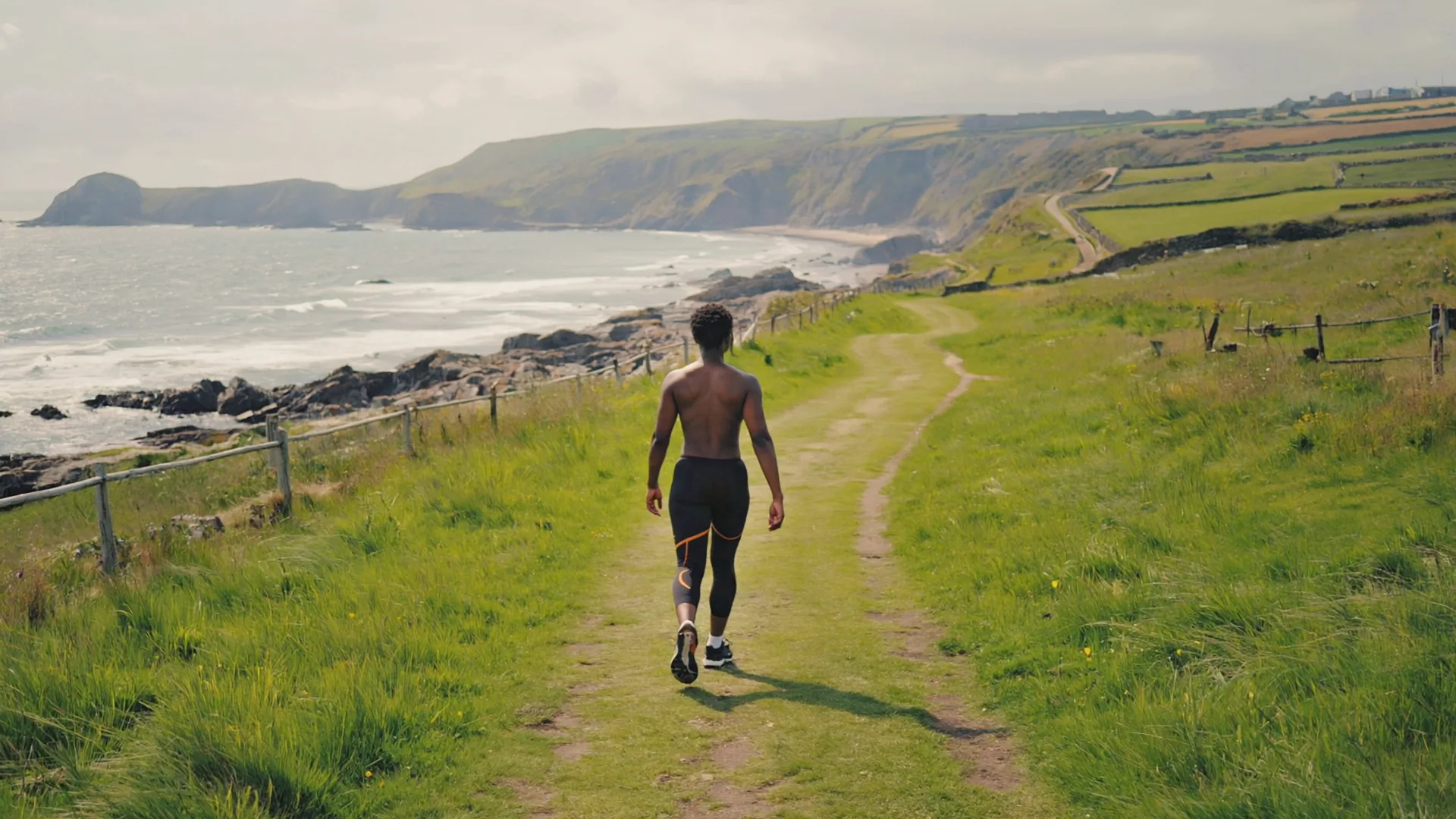 A person walking briskly along a green coastal path in Ireland on a bright overcast day A person walking briskly along a green coastal path in Ireland on a bright overcast day