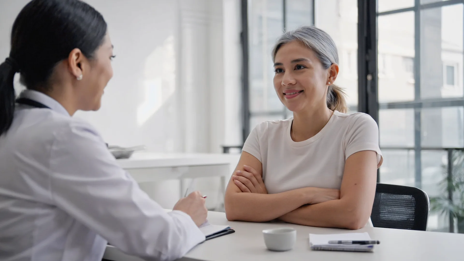 A woman in her 40s in consultation with a clinician in a modern, bright office discussing health options.